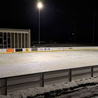 The illuminated natural ice rink in Sils i.D. in the evening