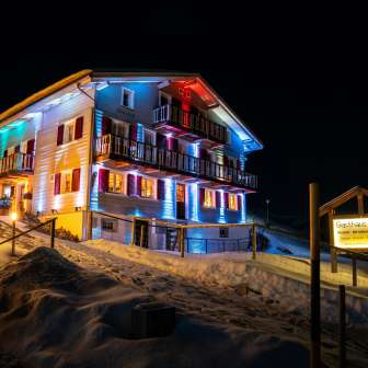 The Gasthaus Alpina is illuminated in the evening in winter